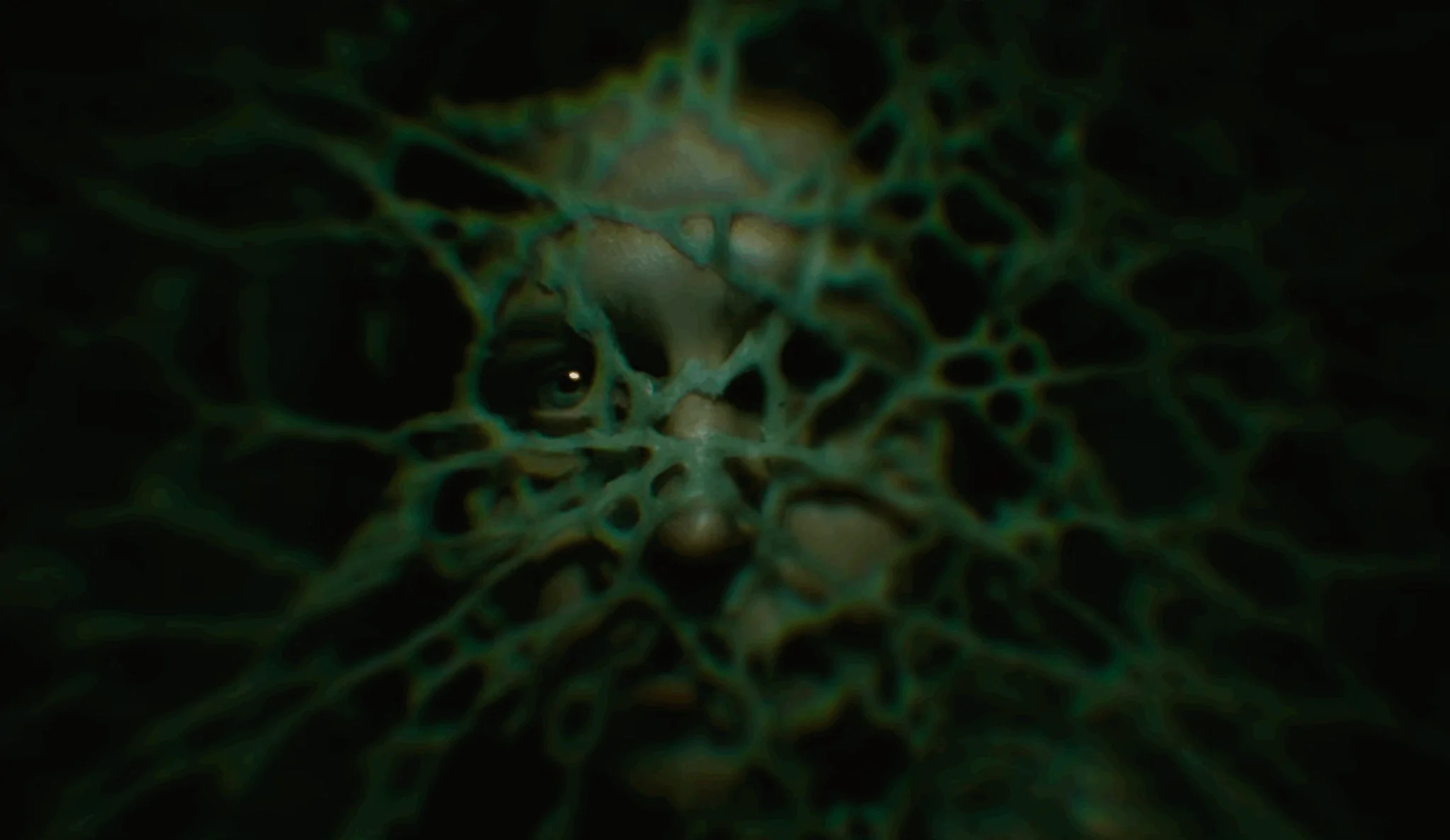 Descendent-2 | film.org.pl Dark, abstract scene with a green, web-like network and a single reflective eye peering through.