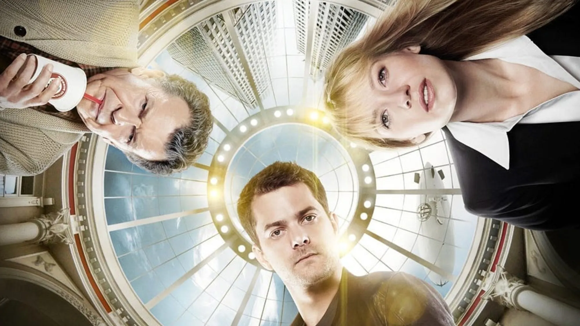 Three people pose for a group photo inside a circular, glass-domed atrium with bright ring lights behind them.
