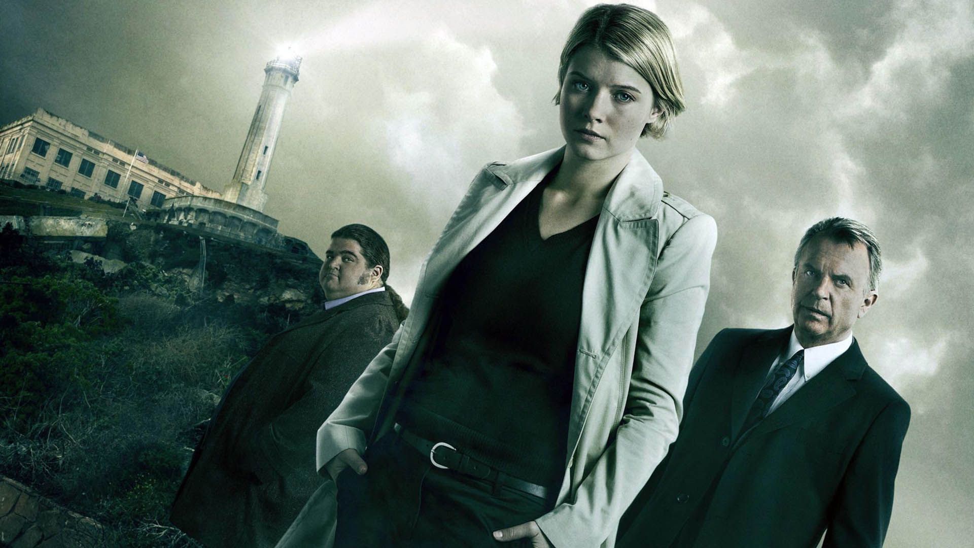 Three investigators stand on a rocky shore with a lighthouse in the background and a stormy sky, suggesting a crime drama poster.