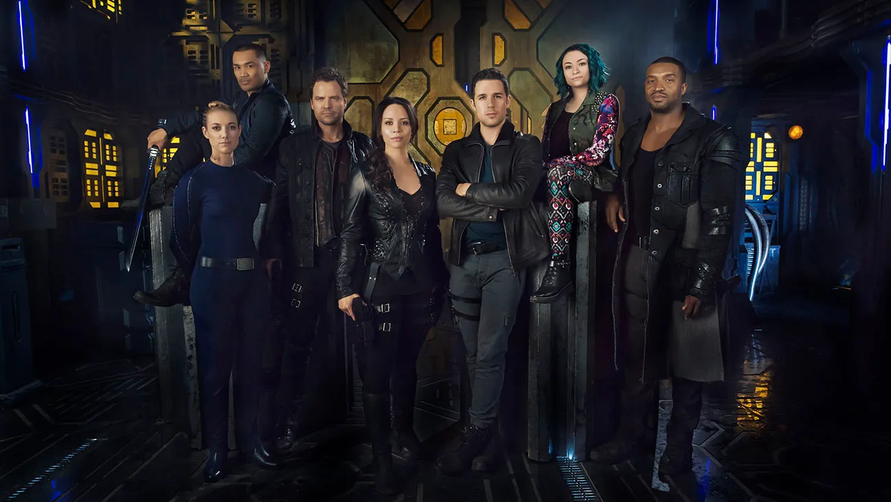 dark-matter | film.org.pl Eight actors in black leather outfits stand in a neon-lit sci-fi set, posing for a team photo.