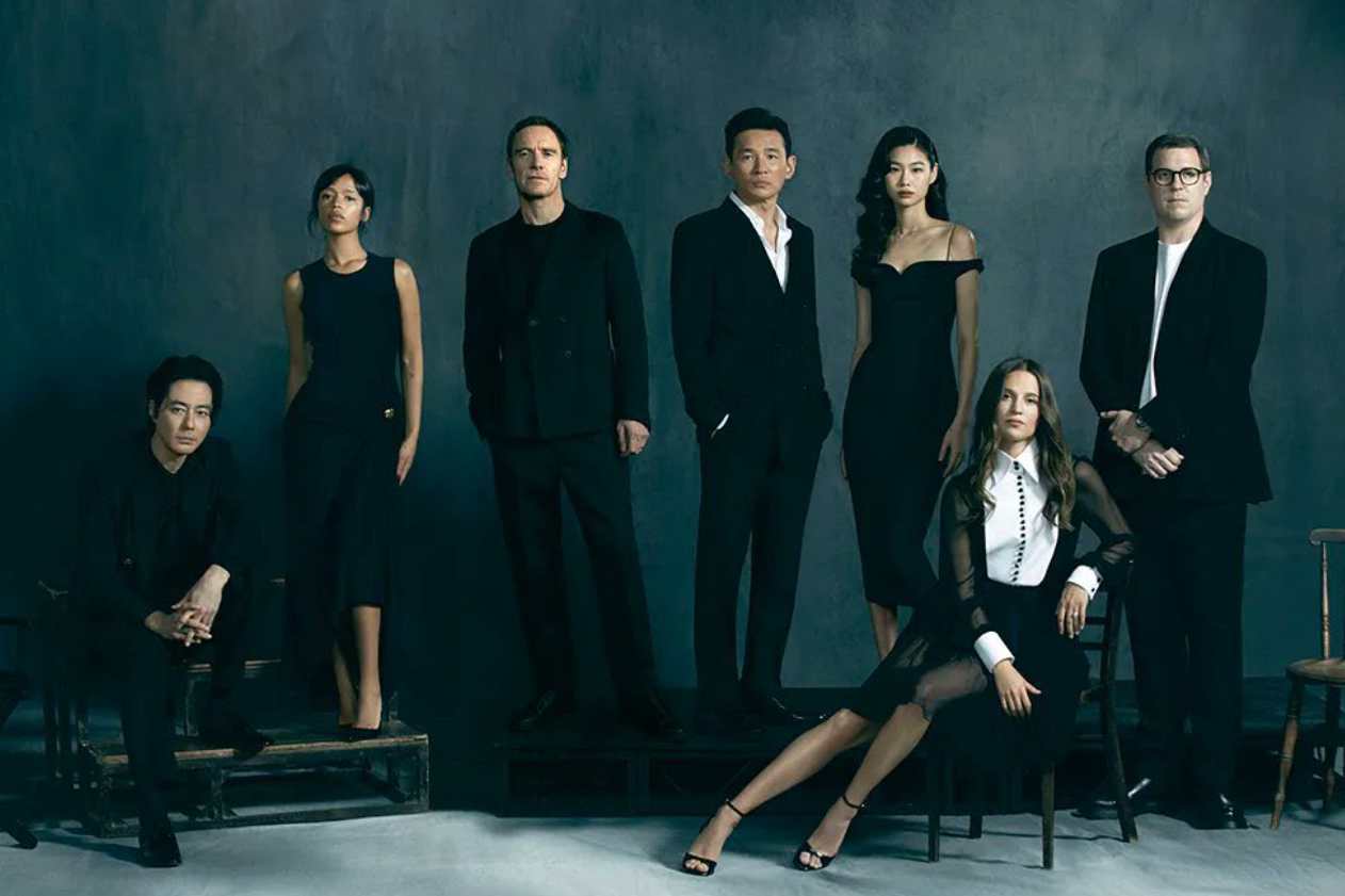 hope | film.org.pl Group portrait of seven adults in a studio wearing black formal attire against a dark teal backdrop.