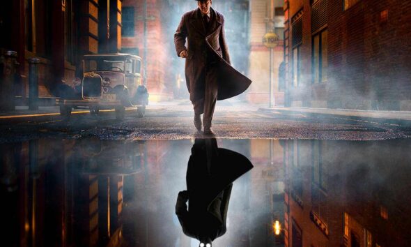 Noir-styled man in a long trench coat and fedora walks down a foggy city street at night, his reflection visible in a puddle.