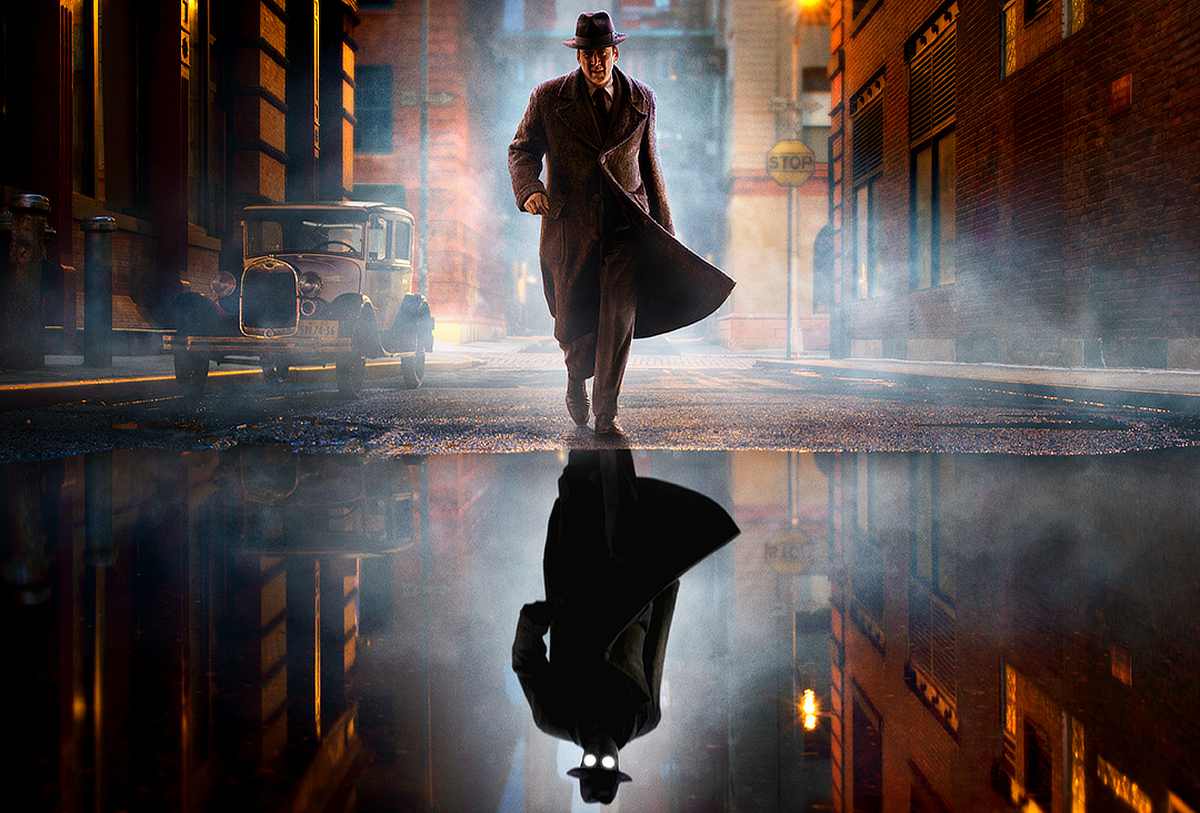 Noir-styled man in a long trench coat and fedora walks down a foggy city street at night, his reflection visible in a puddle.