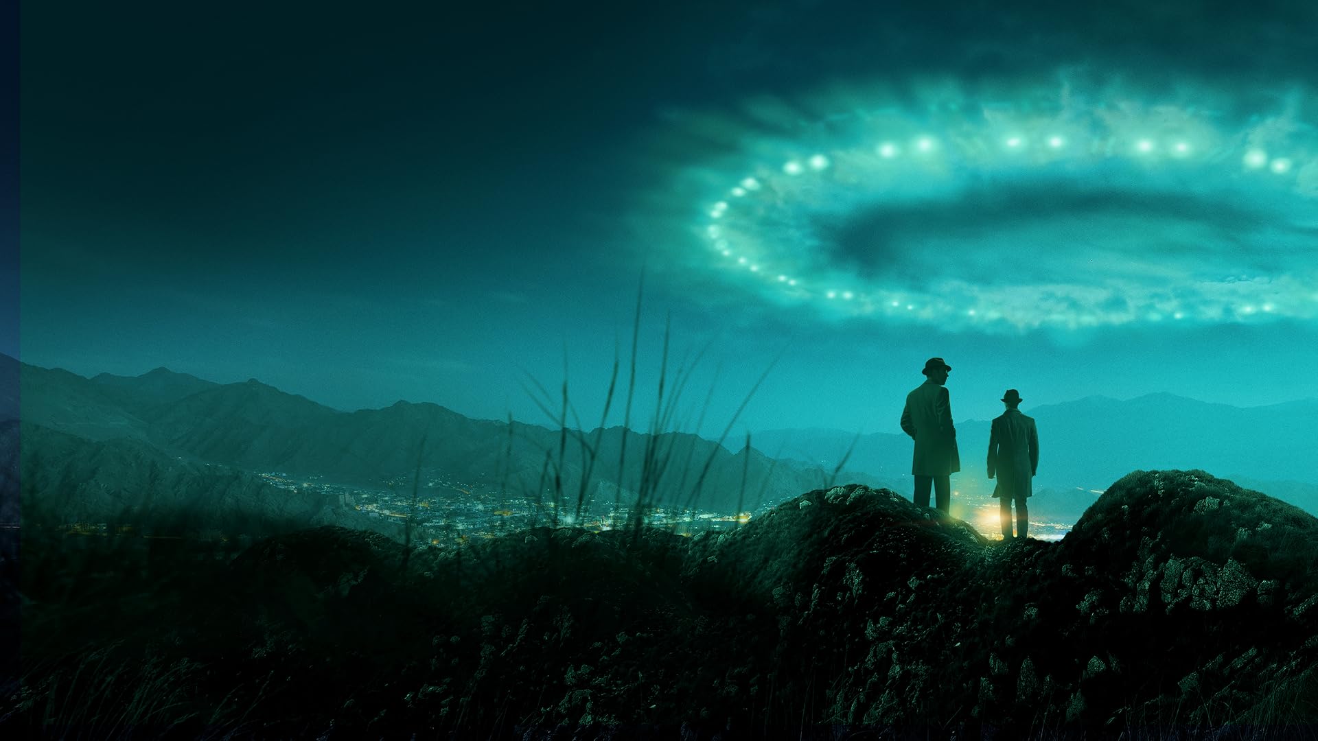Two men in long coats and fedora hats stand on a rocky hill, looking toward a valley city and distant mountains under a teal, glowing sky ring.
