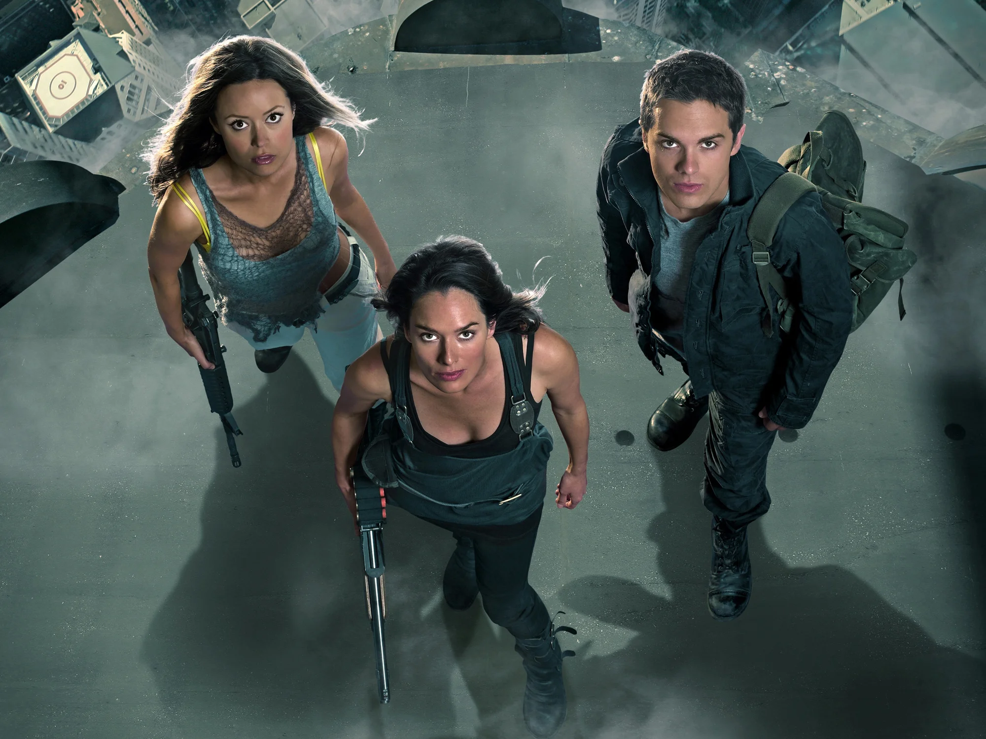 Terminator-Kroniki-Sary-Connor | film.org.pl Top-down view of three people standing on a rooftop, armed and looking up toward the camera, ready for action.