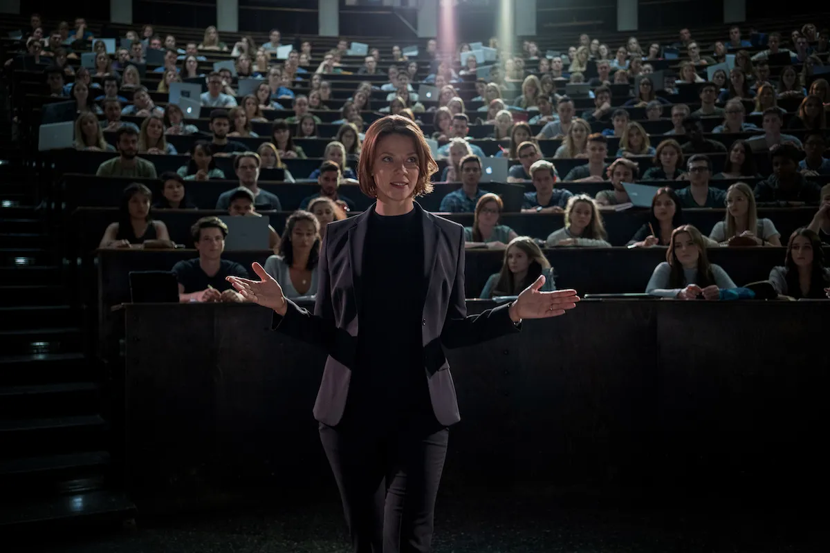 biohakerzy-Biohackers-3 | film.org.pl Female presenter at the front of a large lecture hall addressing a seated audience of students with laptops nearby.