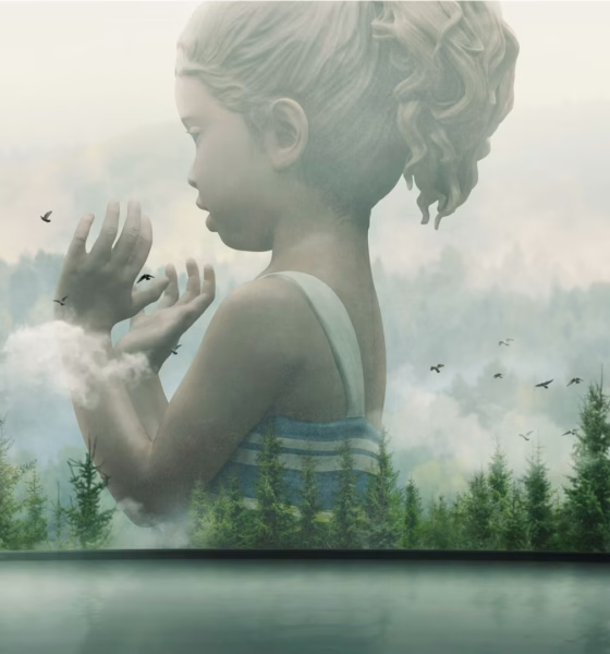 Man standing in a gallery viewing a large double-exposure mural: a girl’s semi-transparent profile blending into a forest landscape.