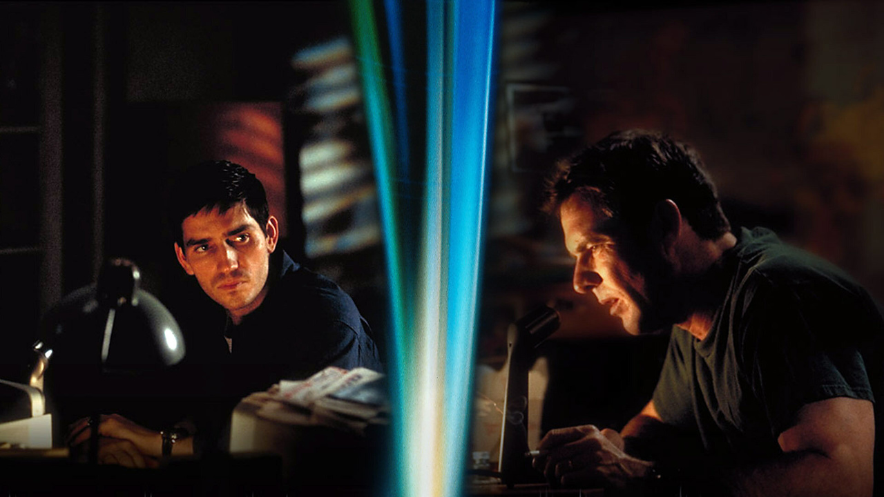 frequency | film.org.pl Two men in a dim room at a cluttered desk; left man watches as the right man speaks into a microphone amid papers and a lamp.