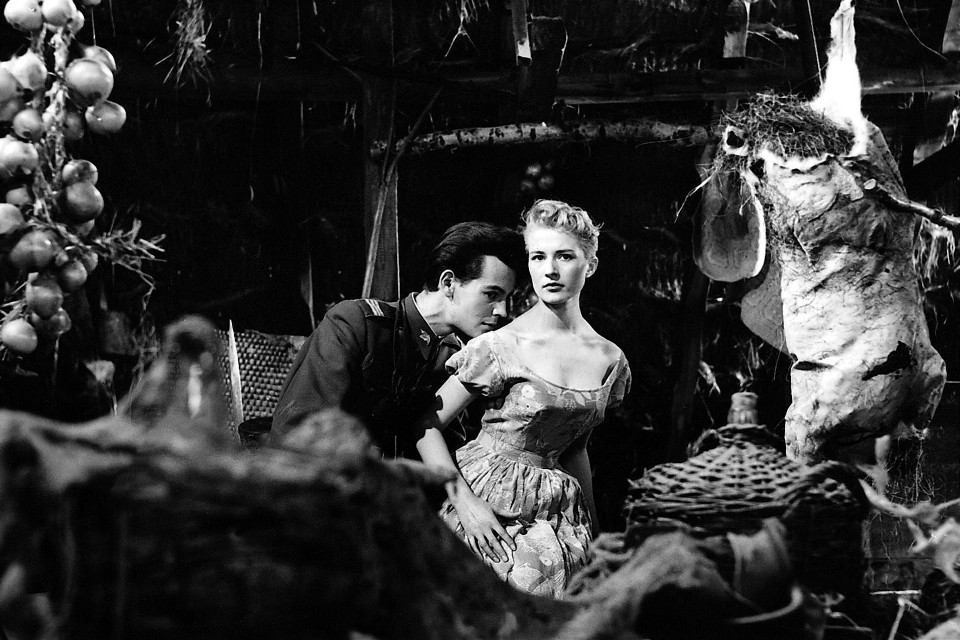 Man leans toward a woman in a dim, rustic market/kitchen setting; a large animal carcass hangs behind them.] The image conveys a vintage, dramatic moment between the two characters.