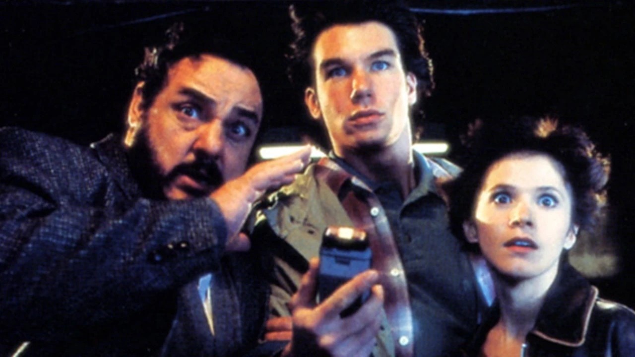 Three people lean in, eyes wide, as they inspect a small handheld device in a dim setting.