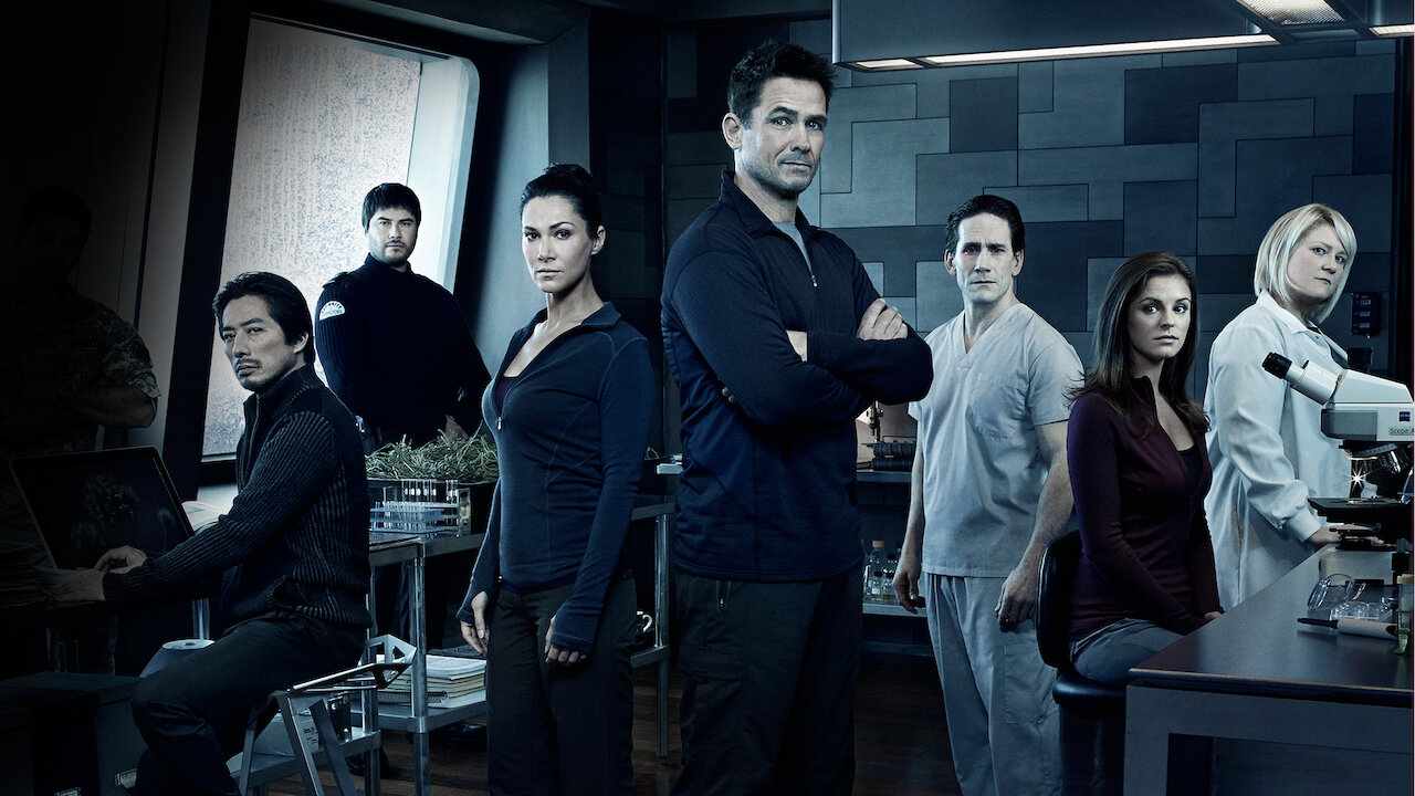 Group of seven researchers in a high-tech lab posing for a team photo, facing the camera.