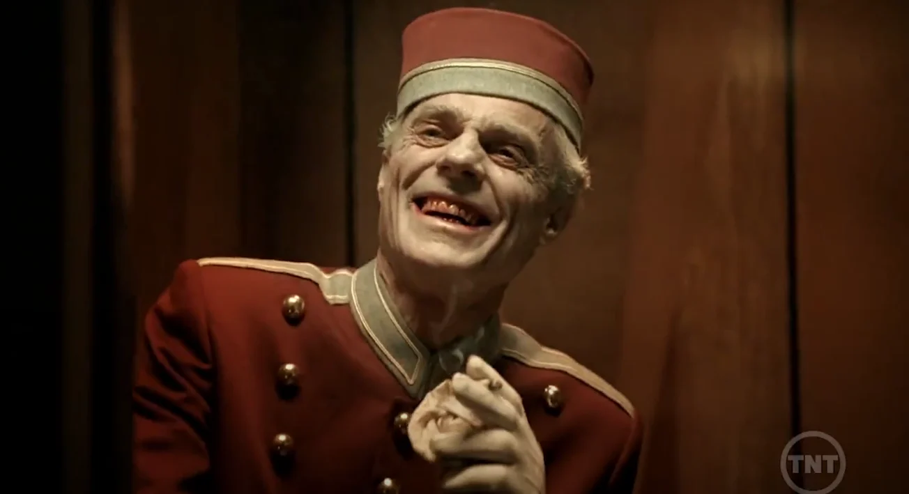 Nightmares-and-Dreamscapes | film.org.pl Elderly man in a red vintage military-style uniform with a matching hat, smiling and pointing playfully on stage.