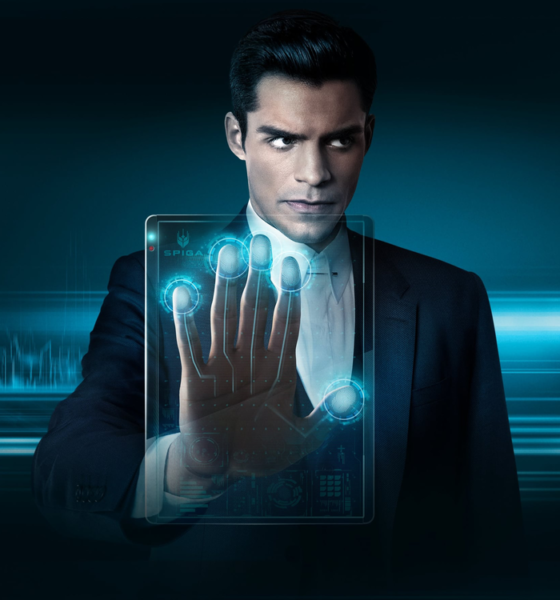Businessman in a dark suit extends his hand toward a glowing blue holographic touchscreen.