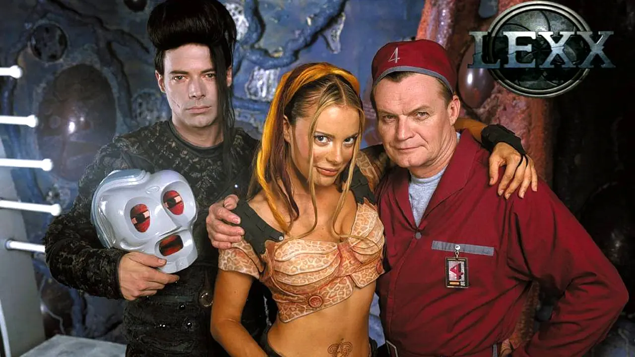 lexx-4 | film.org.pl Three characters pose in a sci-fi set: a man in black holding a gray skull mask, a woman in an orange patterned top, and a man in a red uniform with a badge; LEXX logo in the corner