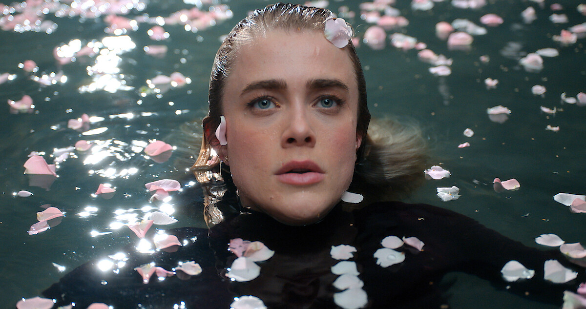 mnifest-turbulencje-2 | film.org.pl Close-up of a woman with wet hair floating in water, pink petals scattered on the surface nearby.