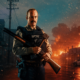 Sheriff in tactical vest stands with a shotgun and axe as flames engulf a street behind him.
