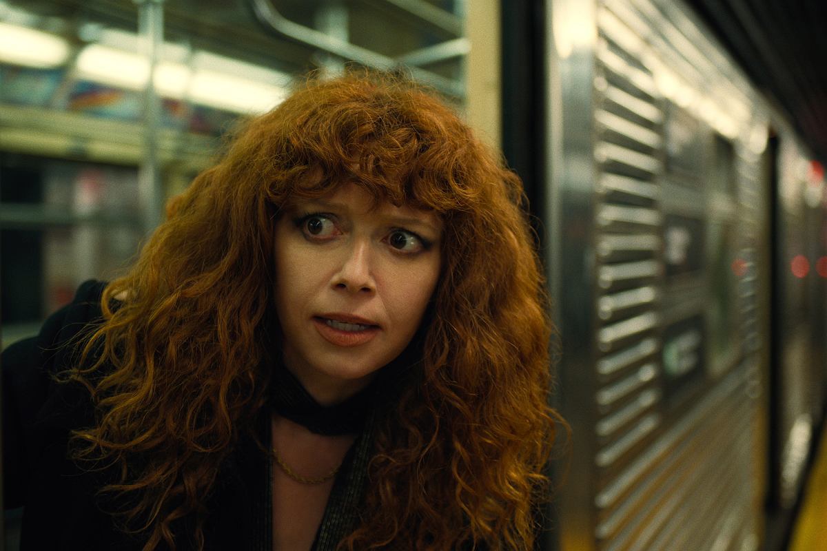 russian-doll-2 | film.org.pl Woman with curly red hair leaning against a subway car, looking anxious or surprised.