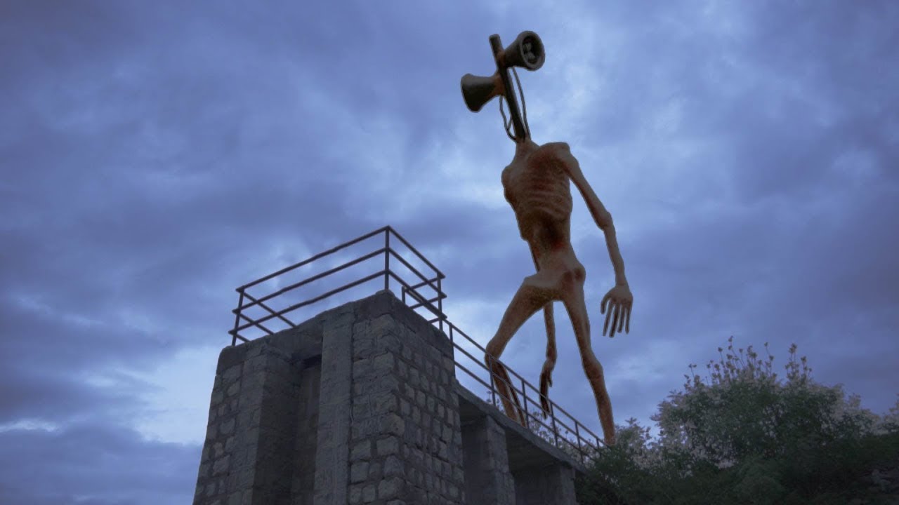Tall rust-colored humanoid statue with a megaphone for a head standing on a stone lookout platform at dusk.
