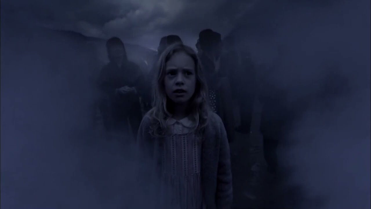 the-4400-2 | film.org.pl A young girl stands in a dark, foggy setting with shadowy figures behind her, looking frightened.