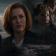 Moody coastal collage: a red-haired woman in the foreground, a doll, and a second woman, with a lighthouse and house in the night.