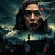 Horror poster: a giant woman’s face with blood on her cheek, an axe looming overhead, and a lone girl on a rooftop in a foggy forest town.