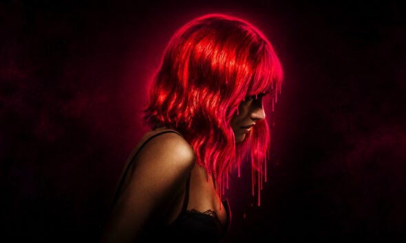 Side profile of a woman with neon pink hair, dripping like paint, wearing a black lace bra against a dark red backdrop.”