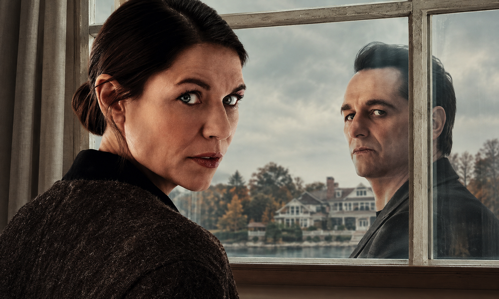Woman indoors, facing the camera with a stern expression, while a man stands outside looking in through a window; autumn houses in the background.