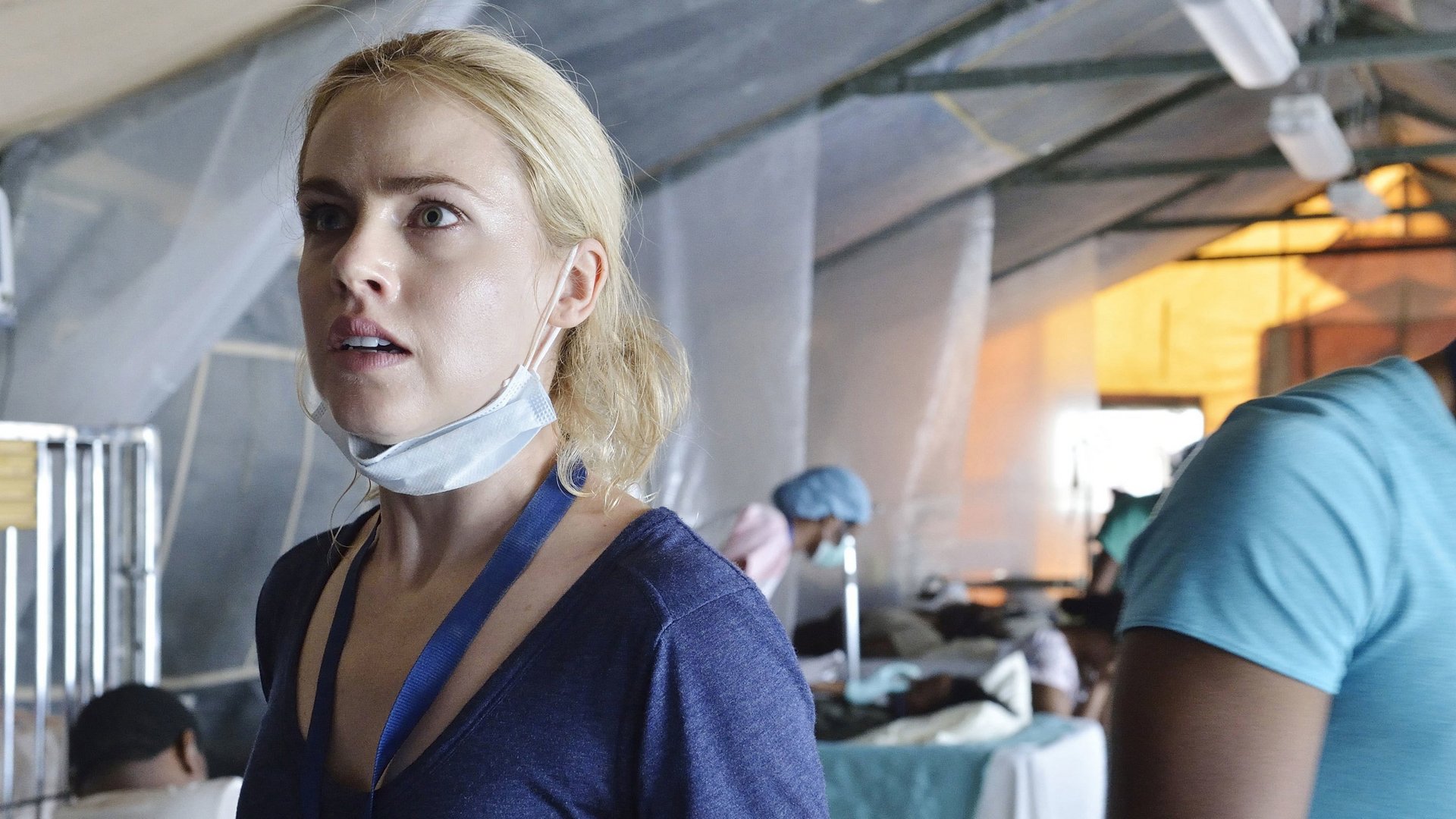 12 Małp 12 Monkeys kadr | film.org.pl Kadr z serialu 12 małp: blond kobieta w niebieskiej bluzce z opuszczoną maseczką na szyi stoi w namiocie szpitalnym. sci-fi