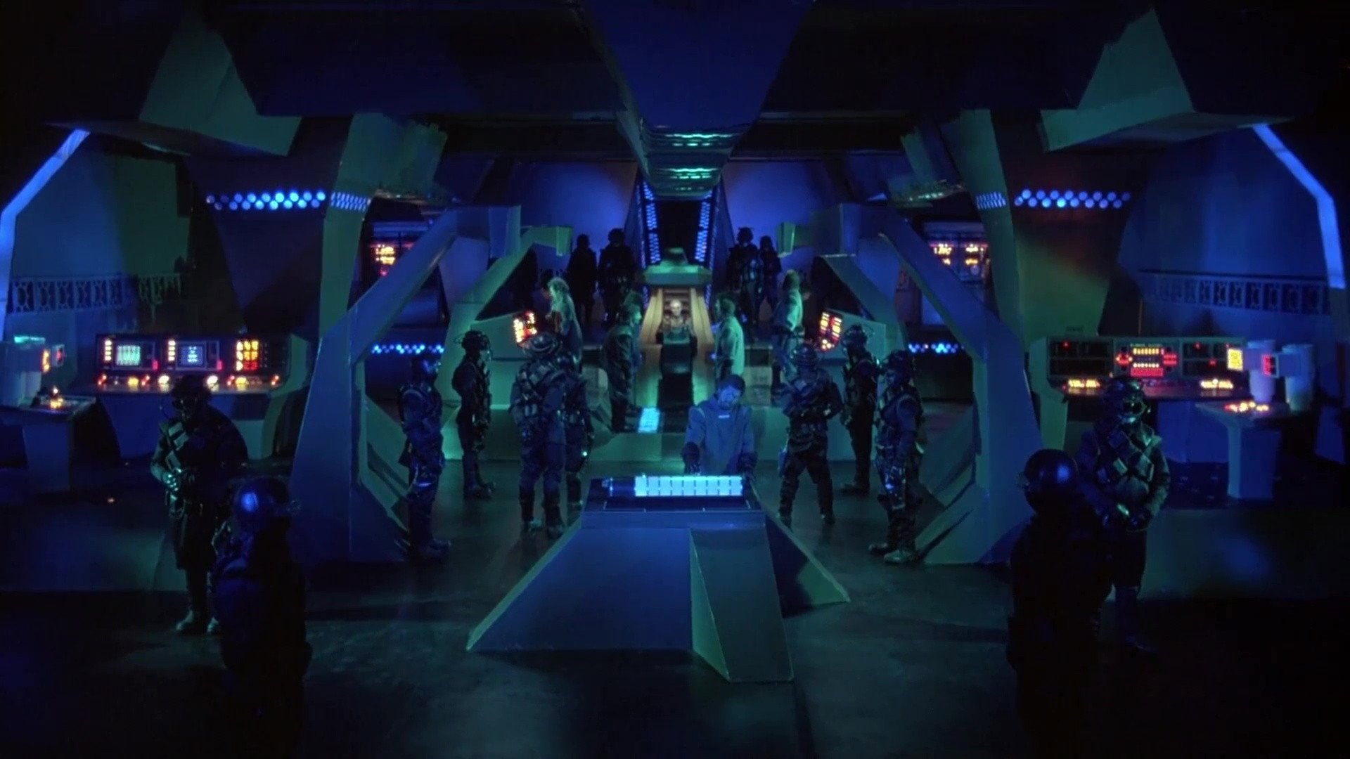 Bitwa wśród gwiazd Battle Beyond the Stars kadr | film.org.pl wnętrze futurystycznego statku z niebieskim oświetleniem, konsoletami i grupą żołnierzy w mundurach.