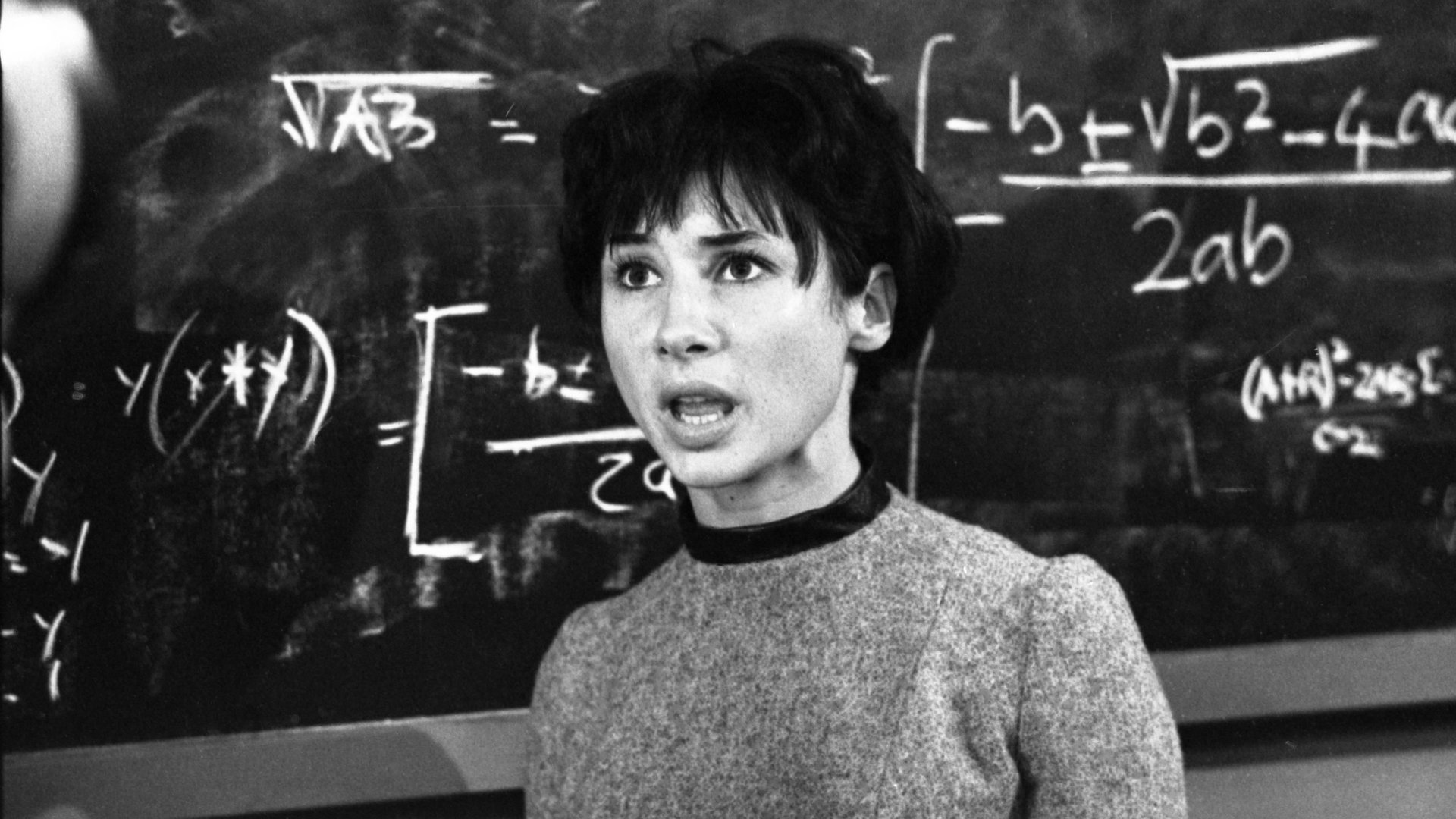 Kadr z serialu Doktor Who: kobieta z krótkimi ciemnymi włosami stoi przed tablicą z wzorami matematycznymi. seriale sci-fi
