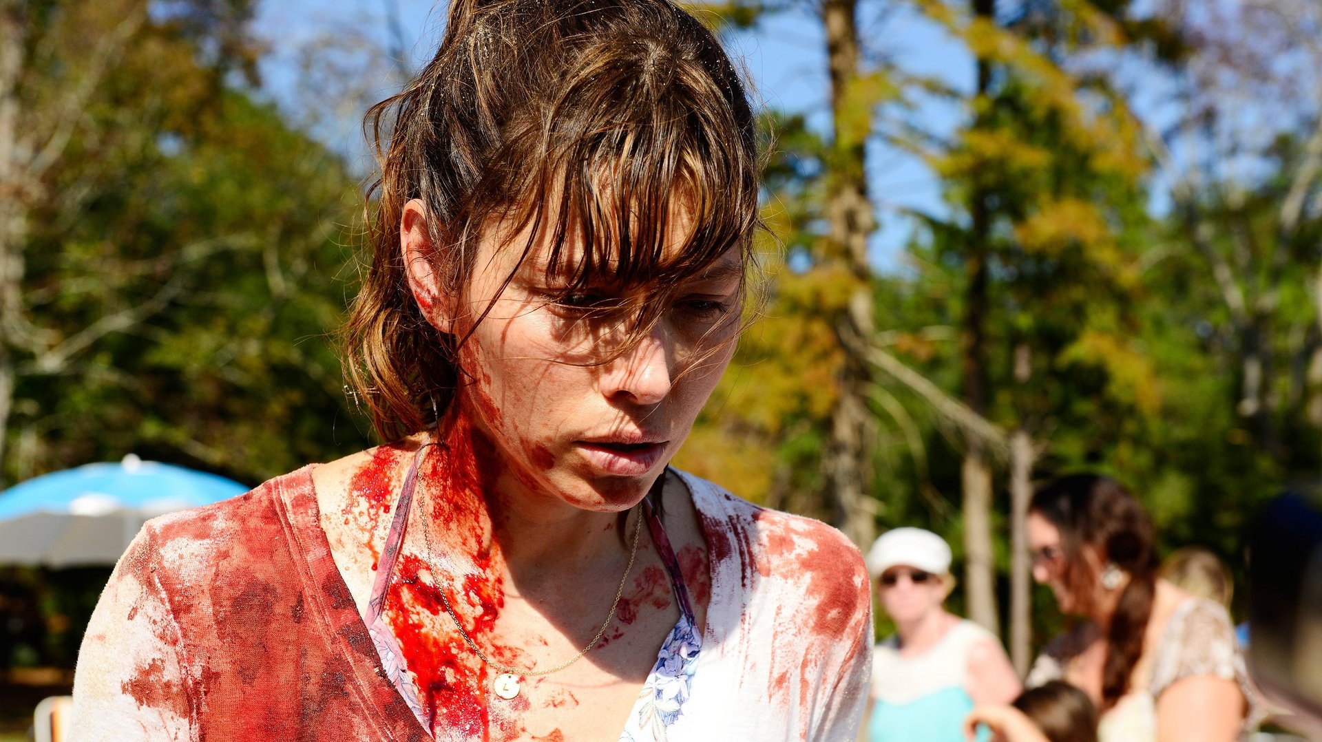 Grzesznica The Sinner kadr | film.org.pl Kadr z serialu Grzesznica: zakrwawiona kobieta z mokrymi włosami patrzy w dół, na tle drzew i ludzi w parku.