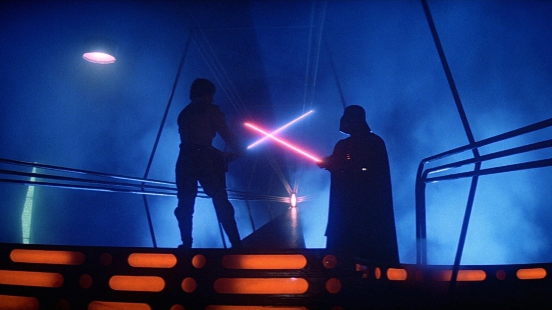 Gwiezdne wojny Część V - Imperium kontratakuje The Empire Strikes Back kadr | film.org.pl Kadr z filmu Gwiezdne wojny: Imperium kontratakuje: dwie sylwetki walczą czerwonymi mieczami świetlnymi na metalowej kładce w niebieskiej mgle. sequele sci-fi