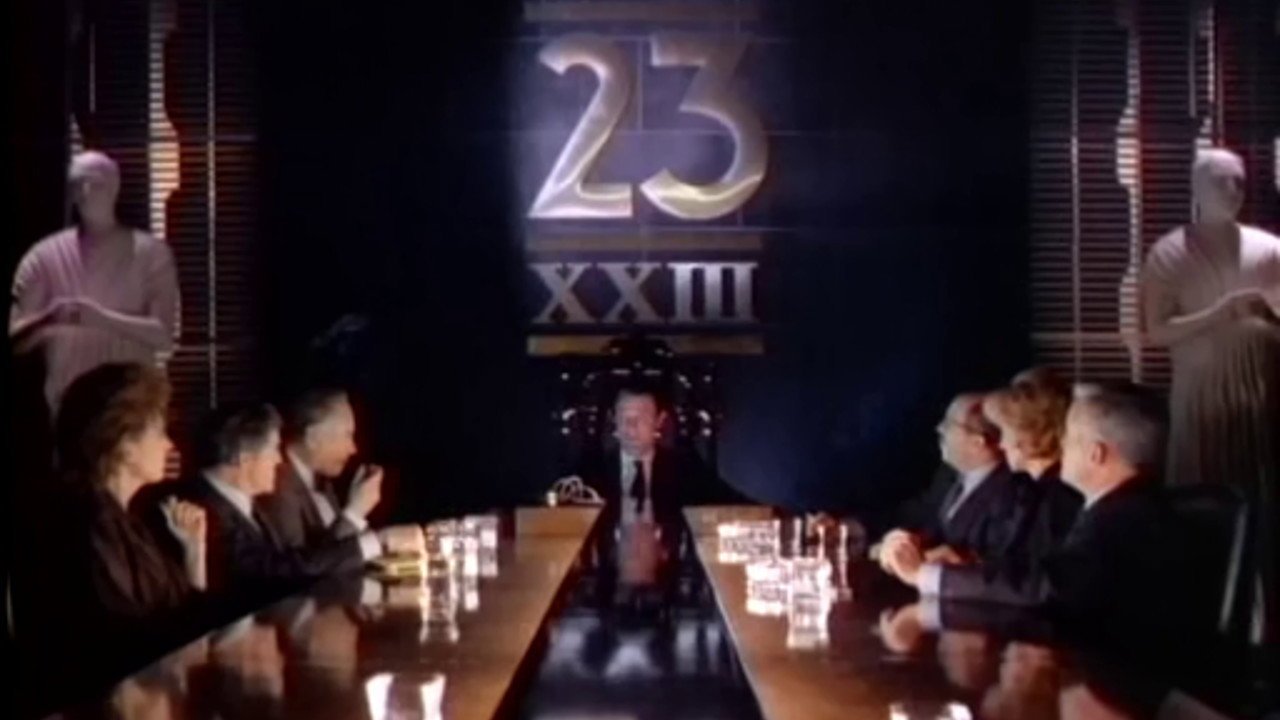 Kadr z serialu Max Headroom: długi stół, po obu stronach siedzący w garniturach, na ścianie złote logo 23 XXIII